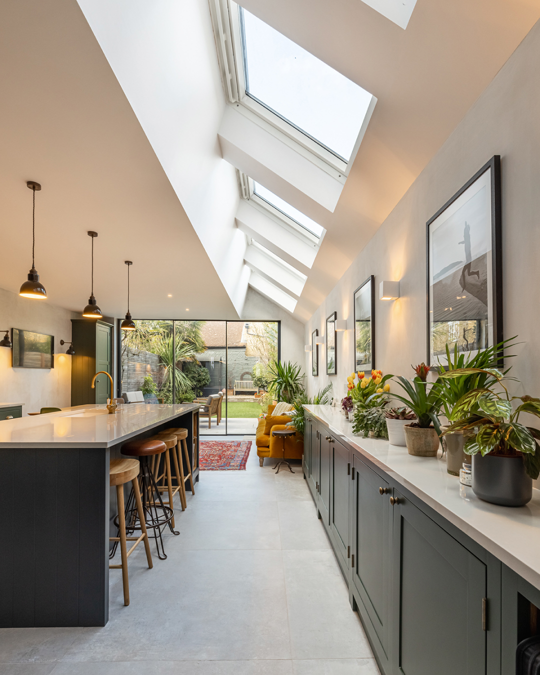 Stunning kitchen extension with vaulted skylights, dark green shaker cabinets, kitchen island and bi-fold doors opening to garden — Hampshire Build design