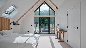 Loft conversion bedroom design Hampshire — vaulted ceiling with Velux rooflight and full-height glazed gable